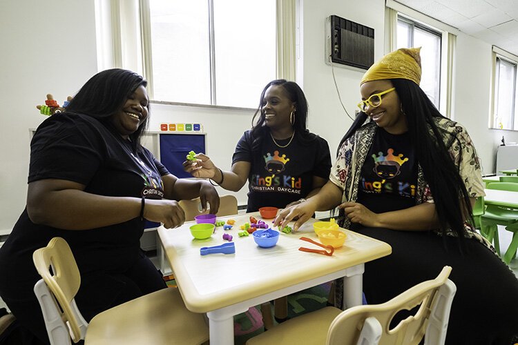 King's Kid Christian Daycare staff members Adrian Robinson, left, Tamara Jones, center, and Lolita Granger laugh Wednesday, July 17, 2024, as they play with toys in one of the classrooms in the Detroit child care center.