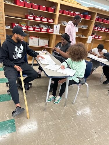 Kaypree Taylor, una empleada de R.I.S.E., trabaja con un joven en sus habilidades de lectura y asiste a otros jóvenes durante el tiempo de clase.