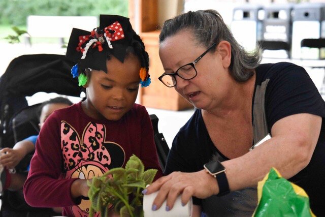 MCREST Support Services Coordinator Judy Dudek (right) teaches a young guest about plants