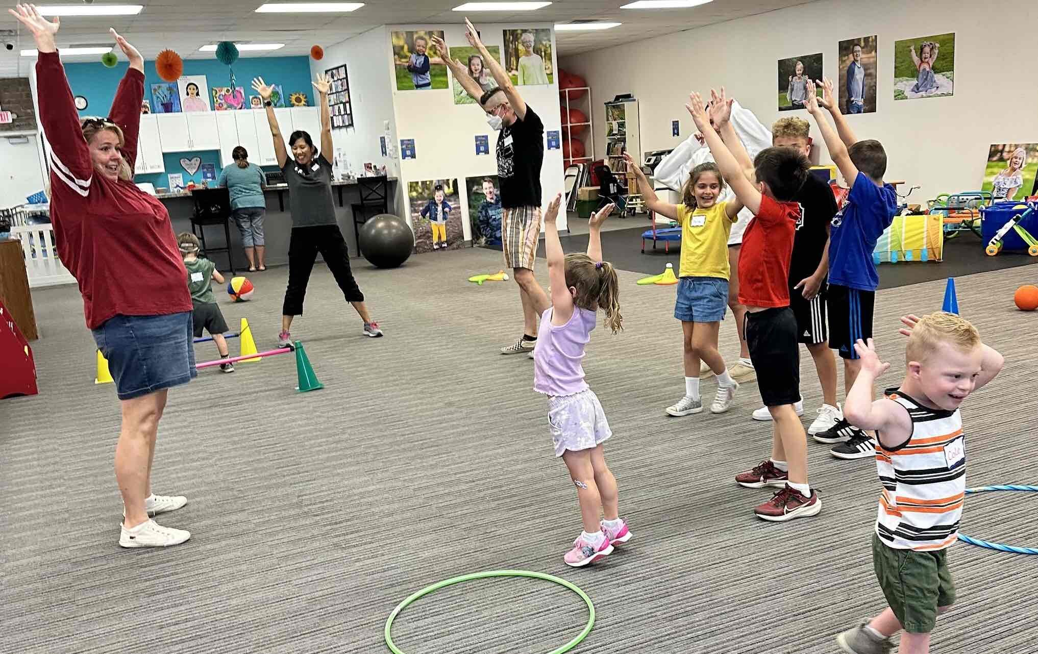 A program leader teaches leading a group through stretches for the Special Olympics Young Athletes program